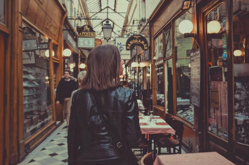 Une femme cougar marche dans un de ces passages typiques de la ville de Paris. Il permette d'aller d'une allée à un autre dans une ambiance ancienne avec des magasins d'art datant d'avant 1900